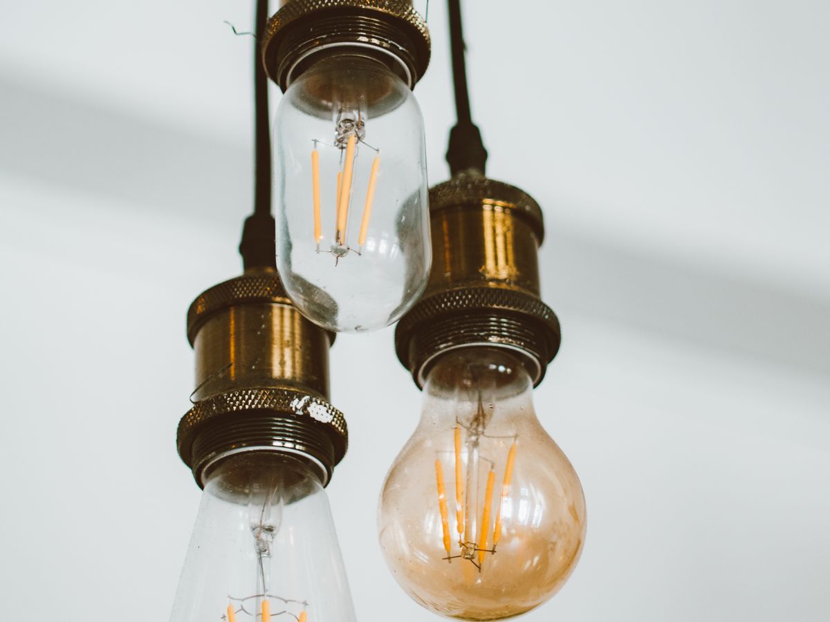Vintage hanging bulbs with visible glowing filaments in a dark interior — the continuous warm spectrum that modern LEDs try to reproduce faithfully.