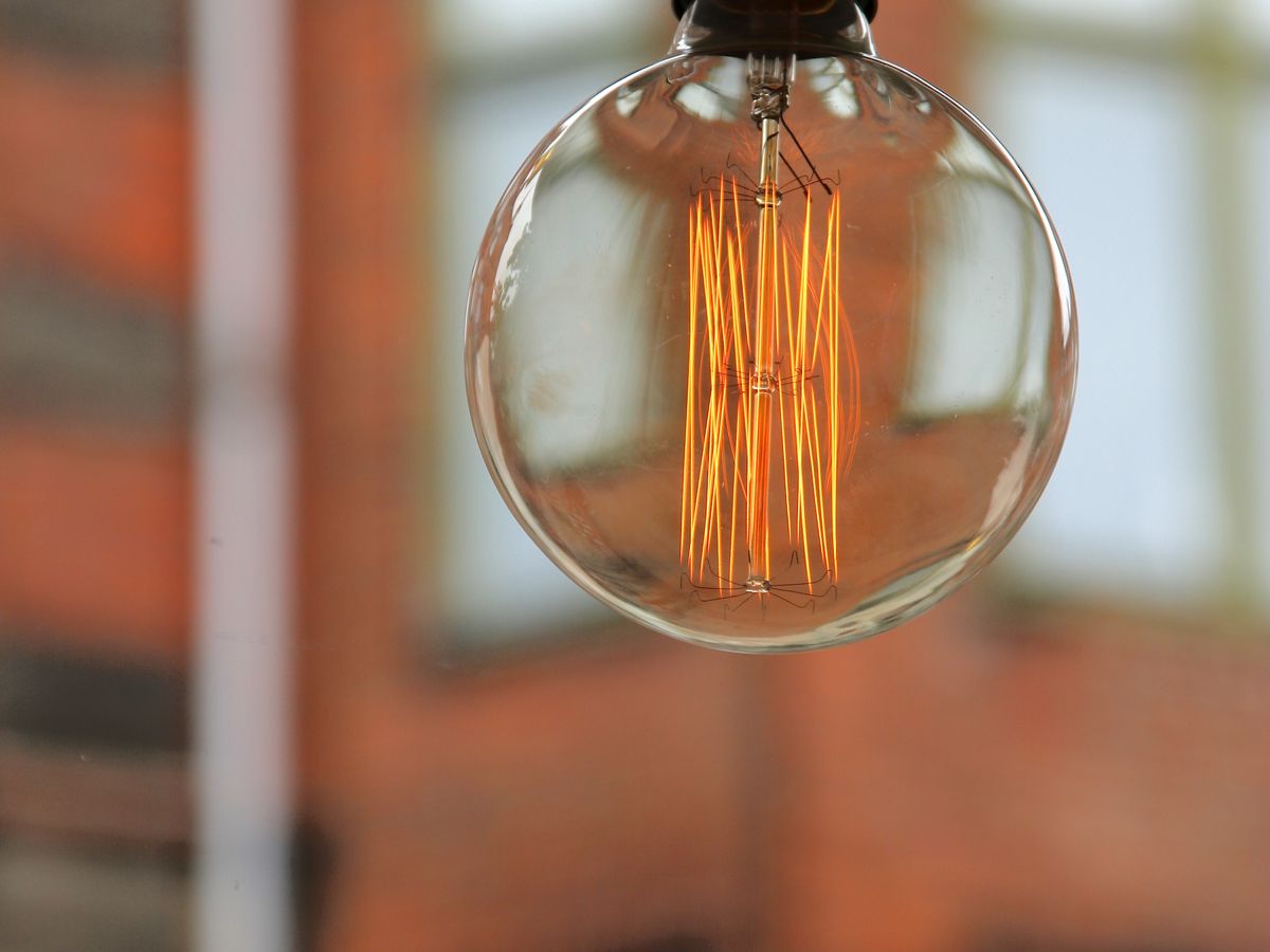 A round bulb glowing against a blurred brick background — the iron-red tones in brick and wood that low R9 rendering flattens.